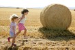 Girls playing with the round wheat dried bales Girls playing with the round wheat dried bales