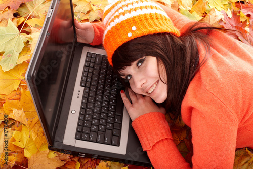 Foto: Girl in autumn orange leaves with laptop.Fall sale. Girl in autumn orange leaves with laptop.Fall sale.