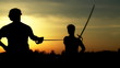 :  Men at sunset fighting with swords