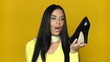 Sexy girl comparing shoes on yellow background