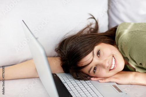 Photo: Pretty teen girl lying on the couch with the laptop Pretty teen girl lying on the couch with the laptop