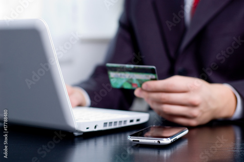 Photo: Businessman using his credit card for an online transaction Businessman using his credit card for an online transaction