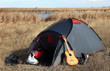 Tent on  yellow wild meadow with blue clouds.