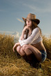 Beautiful slavonic girl in cowboy clothes pose in wheat field