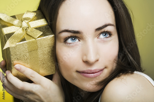 Photo: neugierige junge frau mit geschenk in der hand neugierige junge frau mit geschenk in der hand