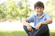 Portrait Of Young Boy Sitting In Park