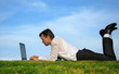 Businessman lie down on grass and working on his computer