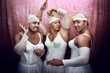 Three strong men in suits of ballerinas. Ñomic photo on a pink b