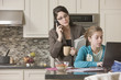 Hispanic mother watching daughter using laptop