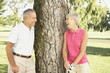 Senior couple leaning against tree on golf course