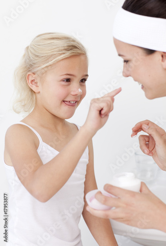 Mother and daughter putting cream on face Mother and daughter putting cream on face