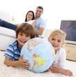 Children playing with a terrestrial globe at home