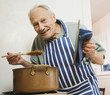 Senior man tasting food in kitchen