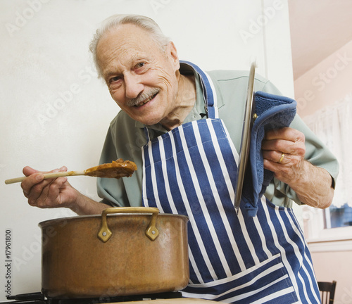 Photo: Senior man tasting food in kitchen Senior man tasting food in kitchen