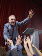 Politician on stage shaking hands with crowd