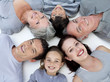 Happy family lying on floor with heads together Happy family lying on floor with heads together