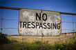 No trespassing sign against backdrop of farmland and houses