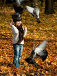 Little girl feeding birds in autumn park