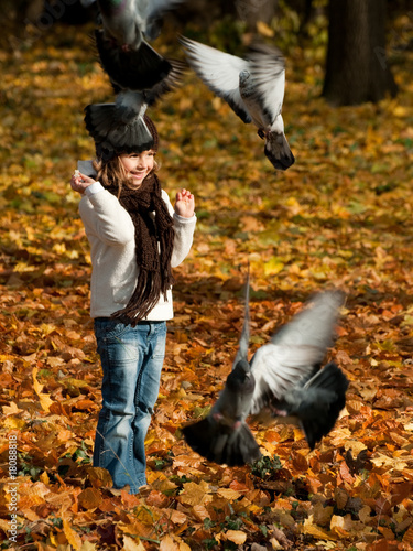 Foto: Little girl feeding birds in autumn park Little girl feeding birds in autumn park