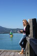femme au bord du lac avec voilier en fond