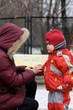 Mum helps the little girl to clasp red winter overalls
