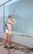 Young woman washing the window