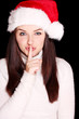 Pretty woman wearing santa hat saying shh