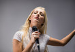 beautiful blond young woman singing into a microphone