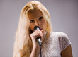 beautiful blond young woman singing into a microphone