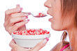 Young woman eating pomegranate with spoon, isolate on white