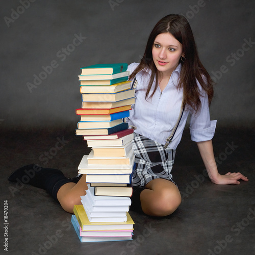 Photo: Schoolgirl with amazement looks at huge pile of textbooks Schoolgirl with amazement looks at huge pile of textbooks