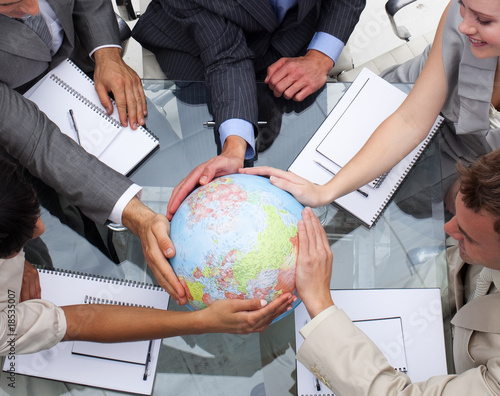 Photo: High angle of business team holding a terrestrial globe High angle of business team holding a terrestrial globe