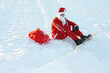 Weihnachtsmann mit Snowboard sitzt im Schnee