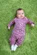 baby laying on his back on green carpet in pink leopard outfit