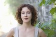 Mid adult woman stands in nature looking directly at camera