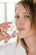 Frau im Bademantel trinkt ein Glas Wasser