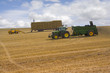 Photo: Straw bales stacked on trailer and tractor spreading fertilizer in sunny rural field Straw bales stacked on trailer and tractor spreading fertilizer in sunny rural field