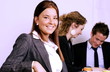 Girl in office smiling, colleagues in background