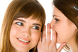 Two happy young girlfriends telling secret