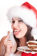 Christmas girl in red santa hat and cake on plate.