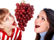 Happy family mother and daughter eat grapes. Isolated.