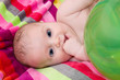 Child lying on a colorful towel with a green balloon