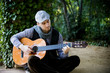 Young artist playing guitar on green garden
