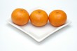 Three mandarins on white square plate
