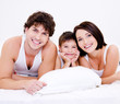 Beautiful young happy family lying in bed