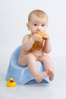 Infant on potty with bottle.