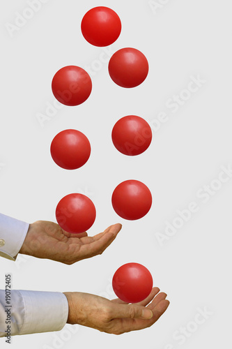 Photo: Businessman with many balls in the air - on grey Businessman with many balls in the air - on grey