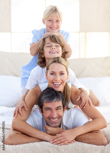 Foto: Happy family having fun on a bed Happy family having fun on a bed