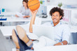 Happy African American editor playing with a basket ball while a