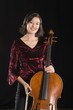 Female cellist stands with cello, portrait